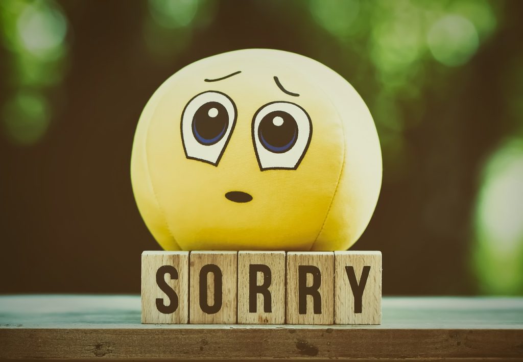 Toy with the form of an emojy placed above a collection of boxes with the word sorry written on it