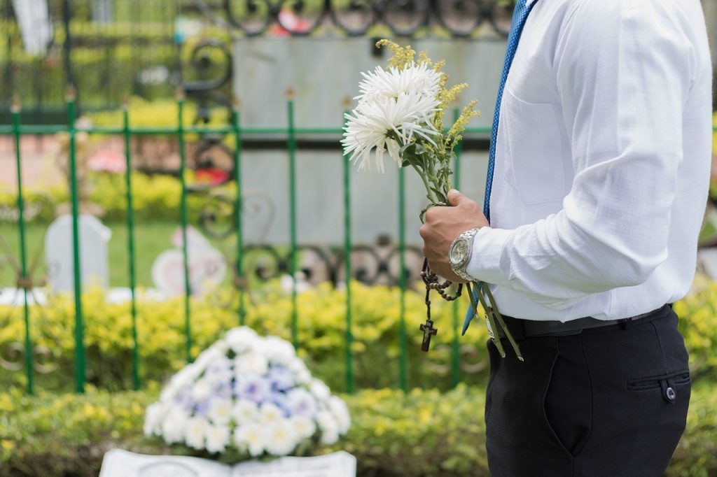 Man holding flowers at a cemetery