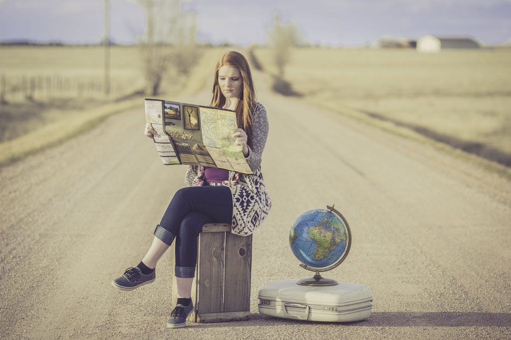 girl sitting on dirt road holding a map
