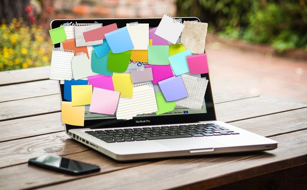 laptop on table with sticky notes pasted on screen